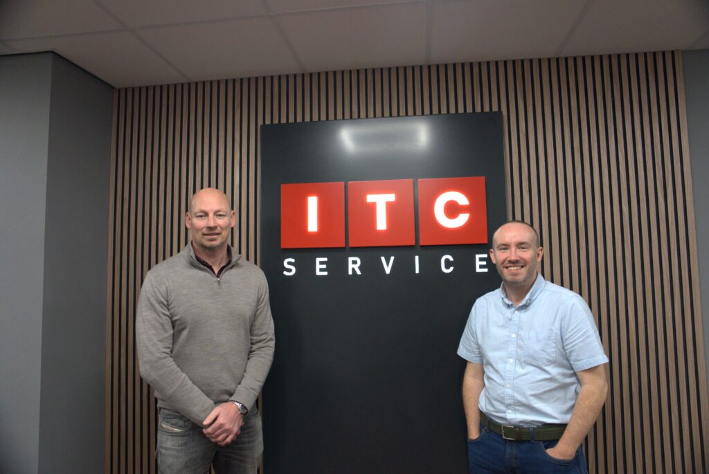 ITC Service co-founders in front of the company logo